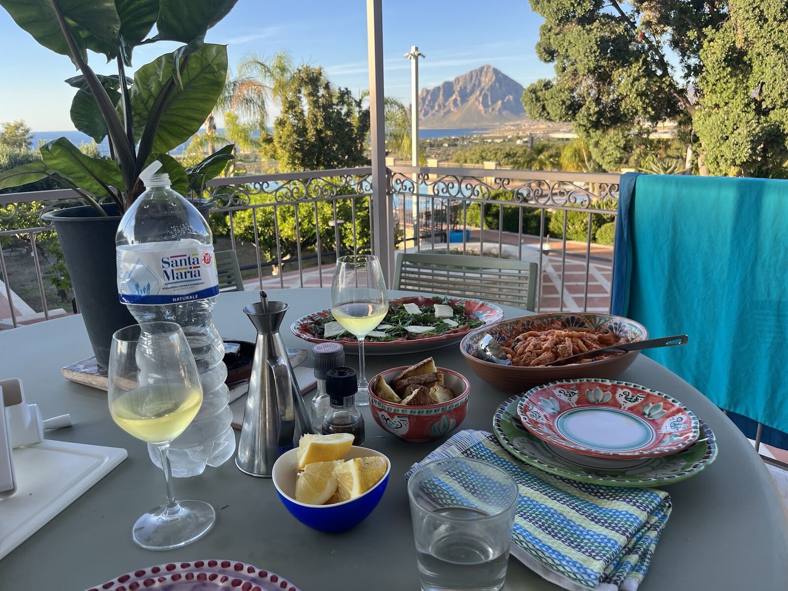 Aperitivo table with wine and Sicilian dishes beside the pool, Monte Cofano behind