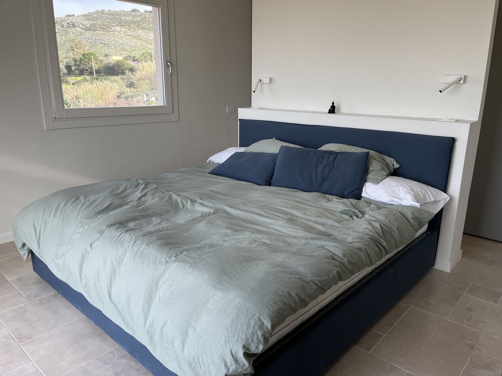 Bedroom with upholstered blue headboard and sage linen