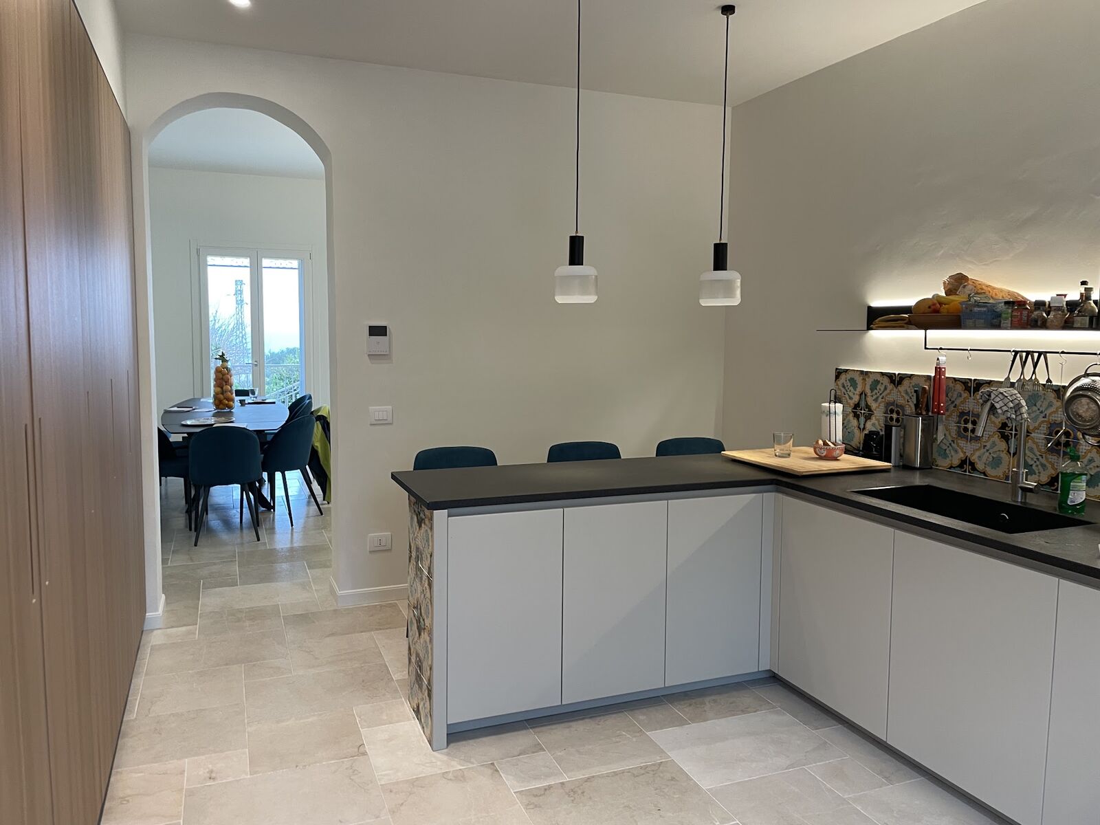 White kitchen opening through an arch to the living room